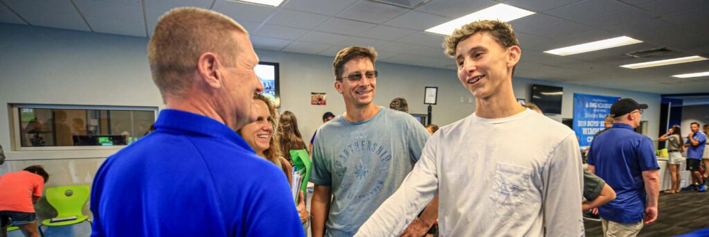 athlete and parents talking with a college coach athlete and parents talking with a college coach